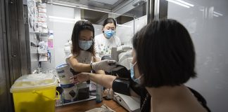 Pandemic-proof Health Screening Services for the Community Ms Fong Jiawen, 22, (left) straps a cuff on Ms Bernice Chai, 40, to take her blood pressure. These health screening booths were originally designed as mass screening swab booths and have been repurposed by CTS’s student organisers.