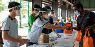 Teenagers, But Already Pros at Crisis Relief Peace and Daniel Lim, 18 and 15, distribute items to migrant workers