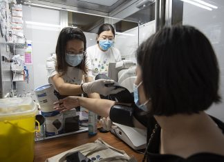 Pandemic-proof Health Screening Services for the Community Ms Fong Jiawen, 22, (left) straps a cuff on Ms Bernice Chai, 40, to take her blood pressure. These health screening booths were originally designed as mass screening swab booths and have been repurposed by CTS’s student organisers.